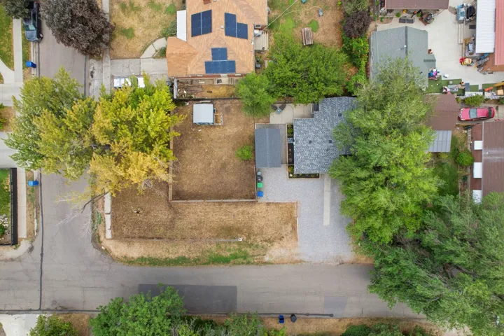 Paved driveway, mature trees, shingle roof, solar panels, and a covered patio structure