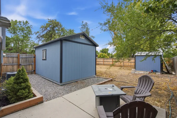 Two detached storage sheds with wood siding, a concrete patio, and a wood fence