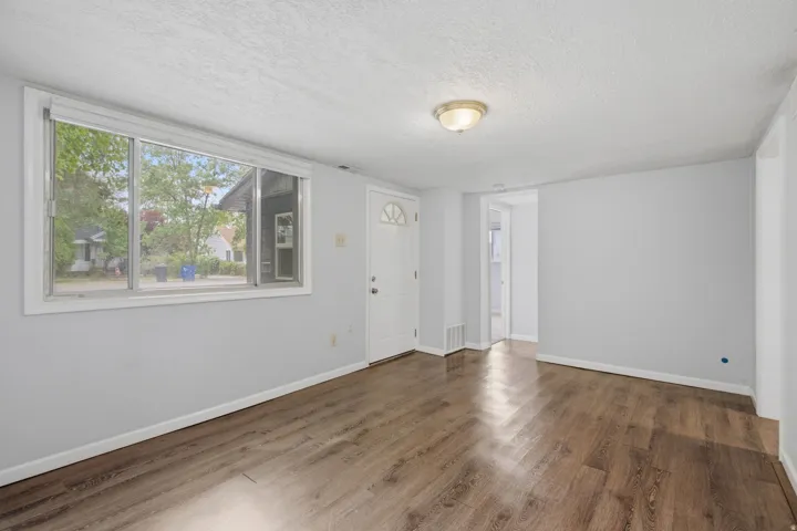 Wood-finish flooring, neutral wall tones, multiple windows, and a ceiling-mounted light fixture