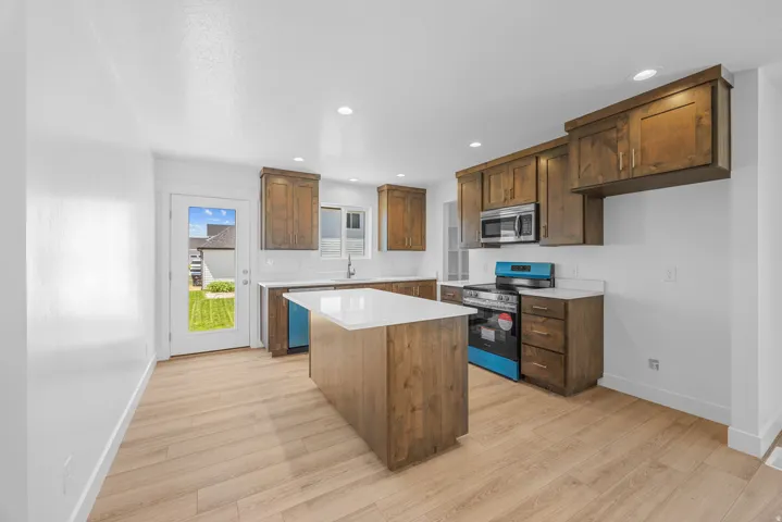 Wood-finish flooring, white countertops, recessed lighting, wood cabinetry, and stainless steel appliances