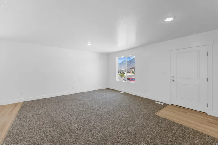 Recessed lighting, white interior door with paneling, wood-finish flooring, carpeting, and a window with mountain scenery