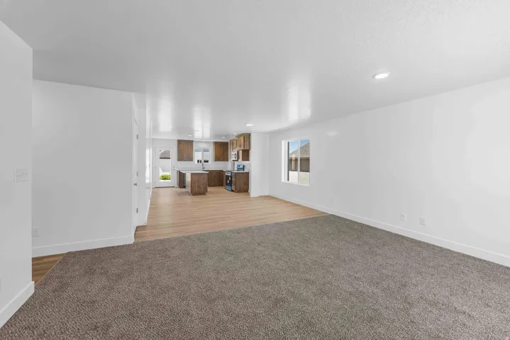 Open-concept living space featuring recessed lighting, a large window, wood-finish flooring, and a kitchen with wood cabinetry and a central island