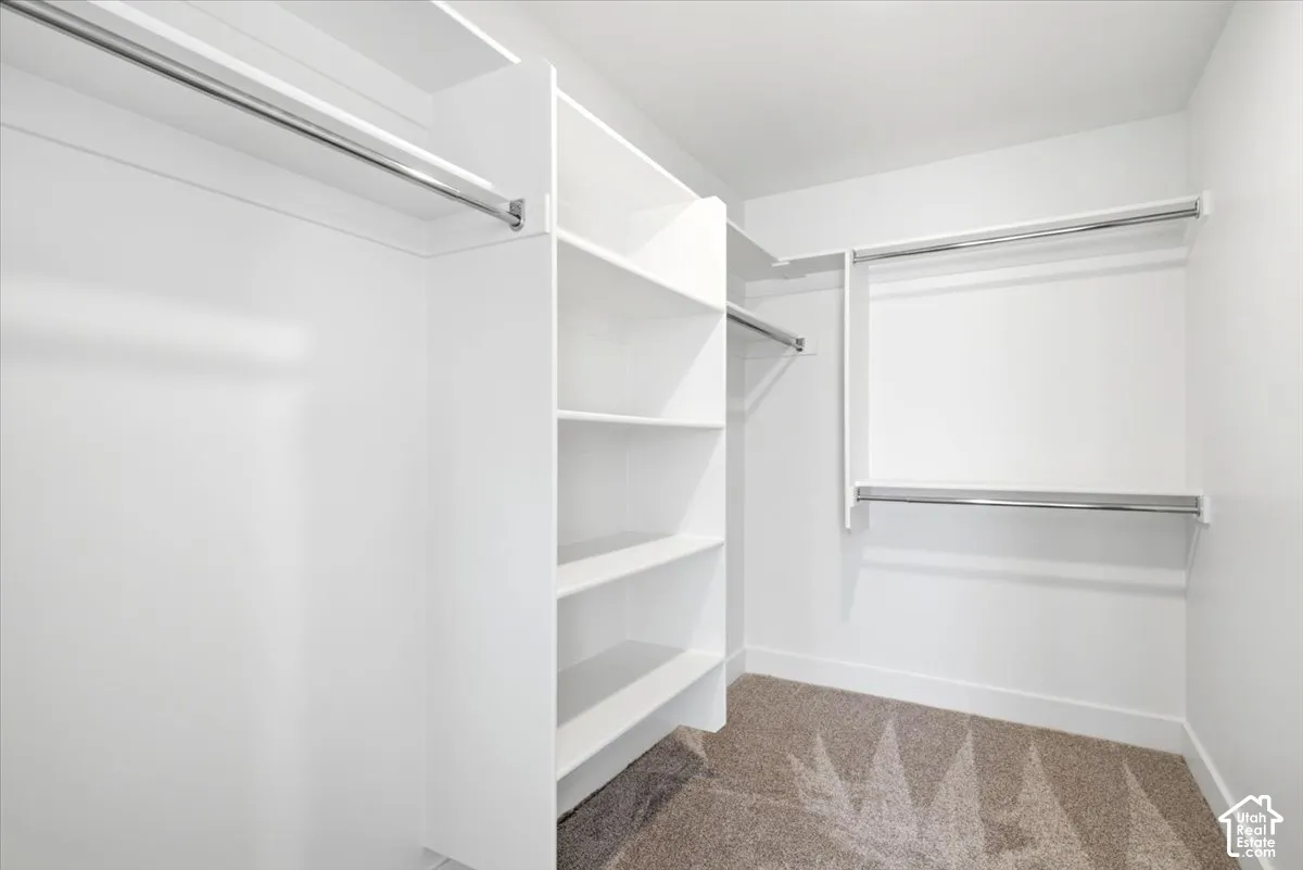 Built-in closet system featuring white shelving, multiple hanging rods, and light-toned carpeting