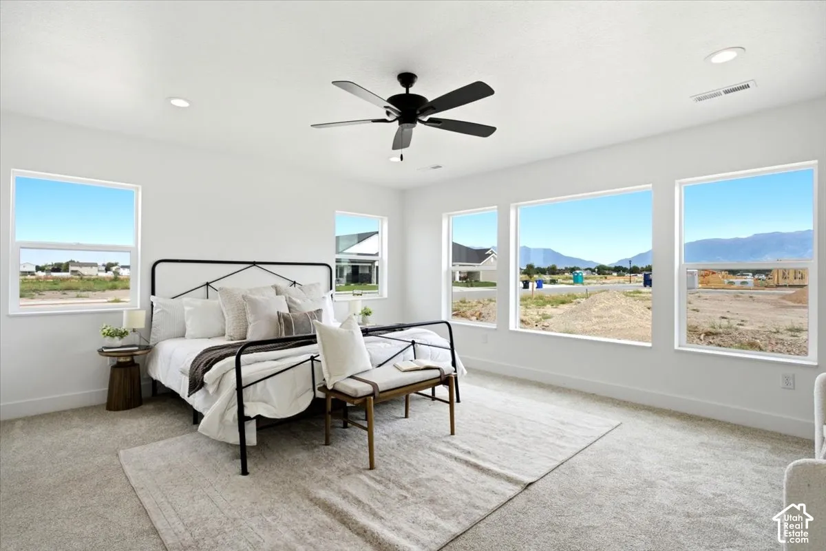Recessed ceiling lighting, ceiling fan, white interior walls, light-toned carpeting, multiple windows