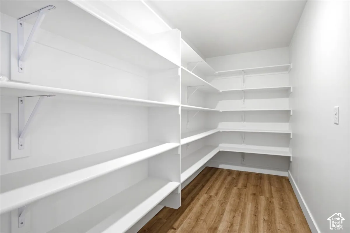 White walls, wood-finish flooring, ample shelving, and white shelving brackets