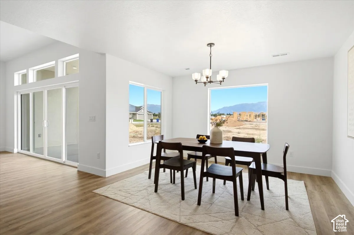 Open-concept room featuring wood-finish flooring, a contemporary chandelier, large picture windows, and sliding glass doors with transom windows