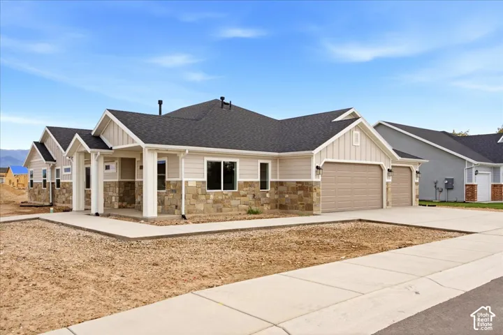 Single-level exterior featuring horizontal siding, natural stone, a multi-gabled roofline, and a three-car garage