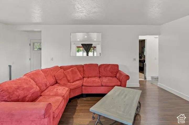 Hardwood-style flooring with white baseboards, bright white walls, and a recessed doorway