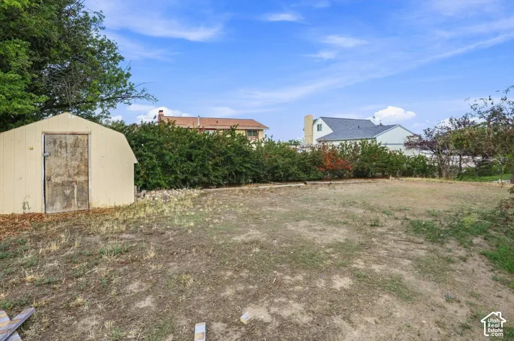 Expansive outdoor space featuring a detached storage shed, mature perimeter landscaping, and a broad grassy area