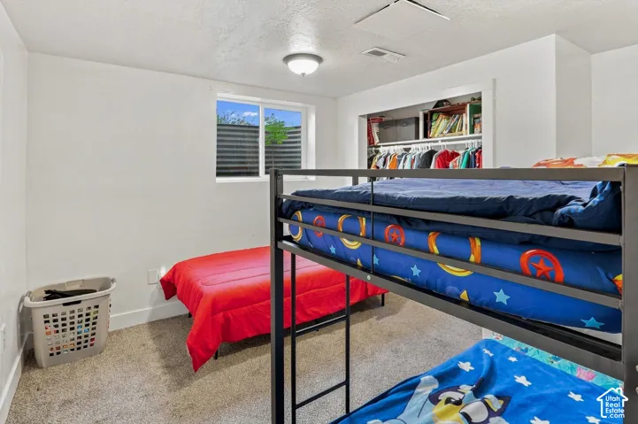 White walls, gray carpet, and a window with a security grate