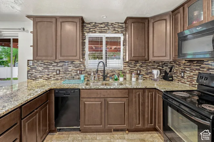 Kitchen featuring wood-finish cabinetry, granite countertops, a mosaic tile backsplash, and stainless steel appliances