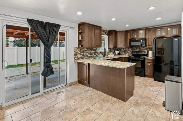 Kitchen featuring a built-in island with countertop seating, tiled backsplash, and recessed lighting