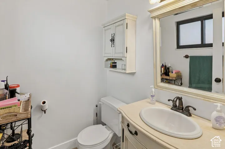 Wall-mounted cabinet with distressed finish, single vanity with oval basin, decorative framed mirror, and a window with dark trim
