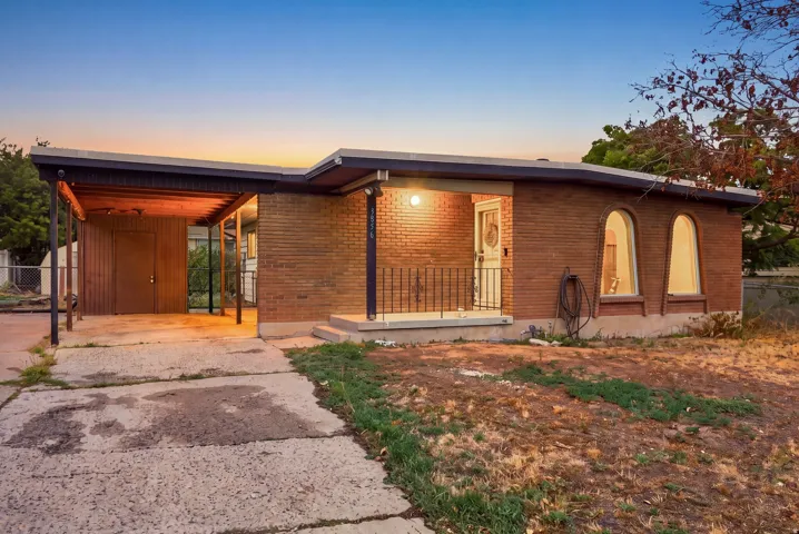 Brick exterior facade with a covered entry, adjacent carport, and arched window features
