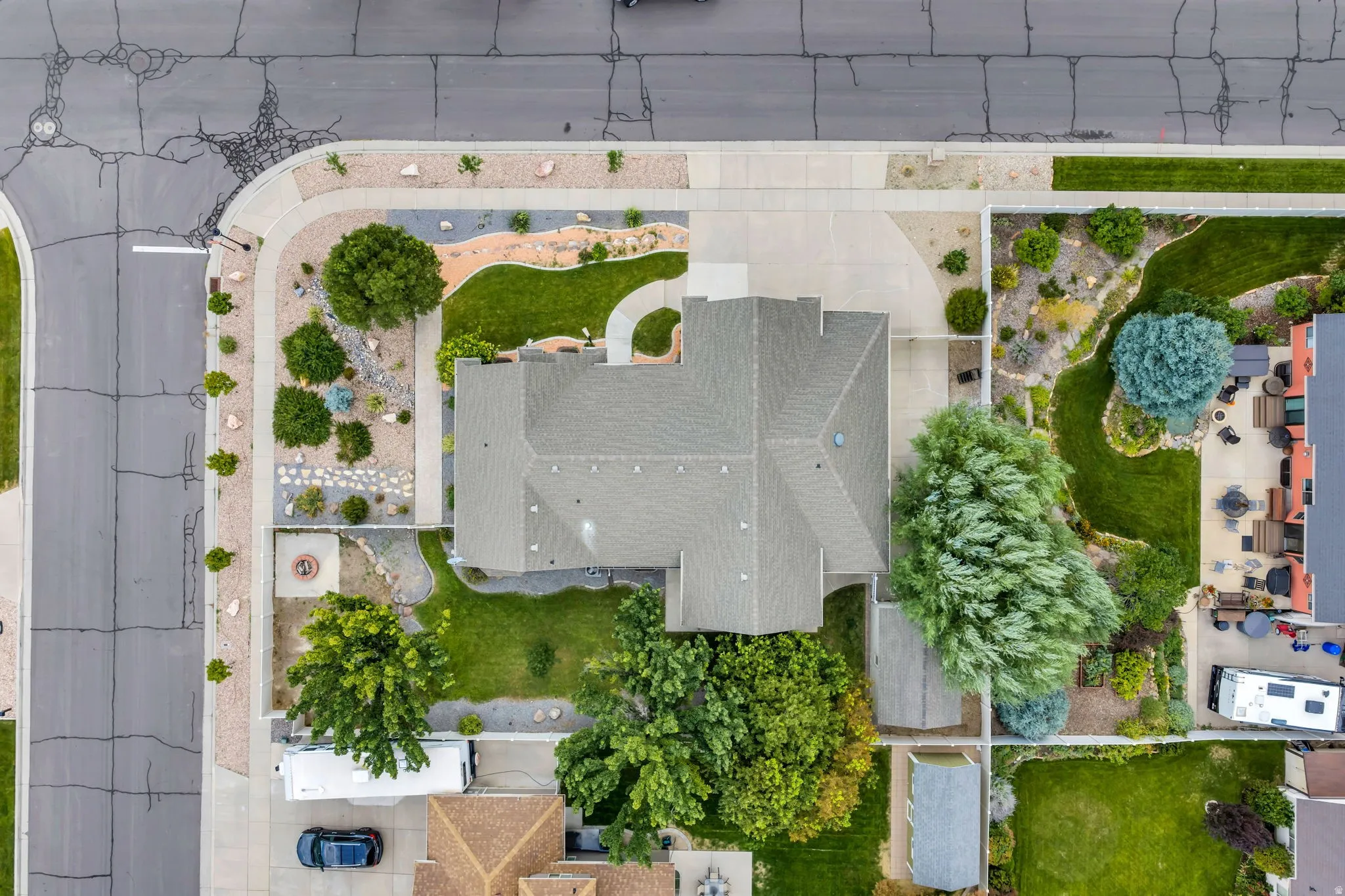 Aerial view showcasing a residence with a generous flat roof, mature landscaping throughout the grounds, and defined hardscaped pathways
