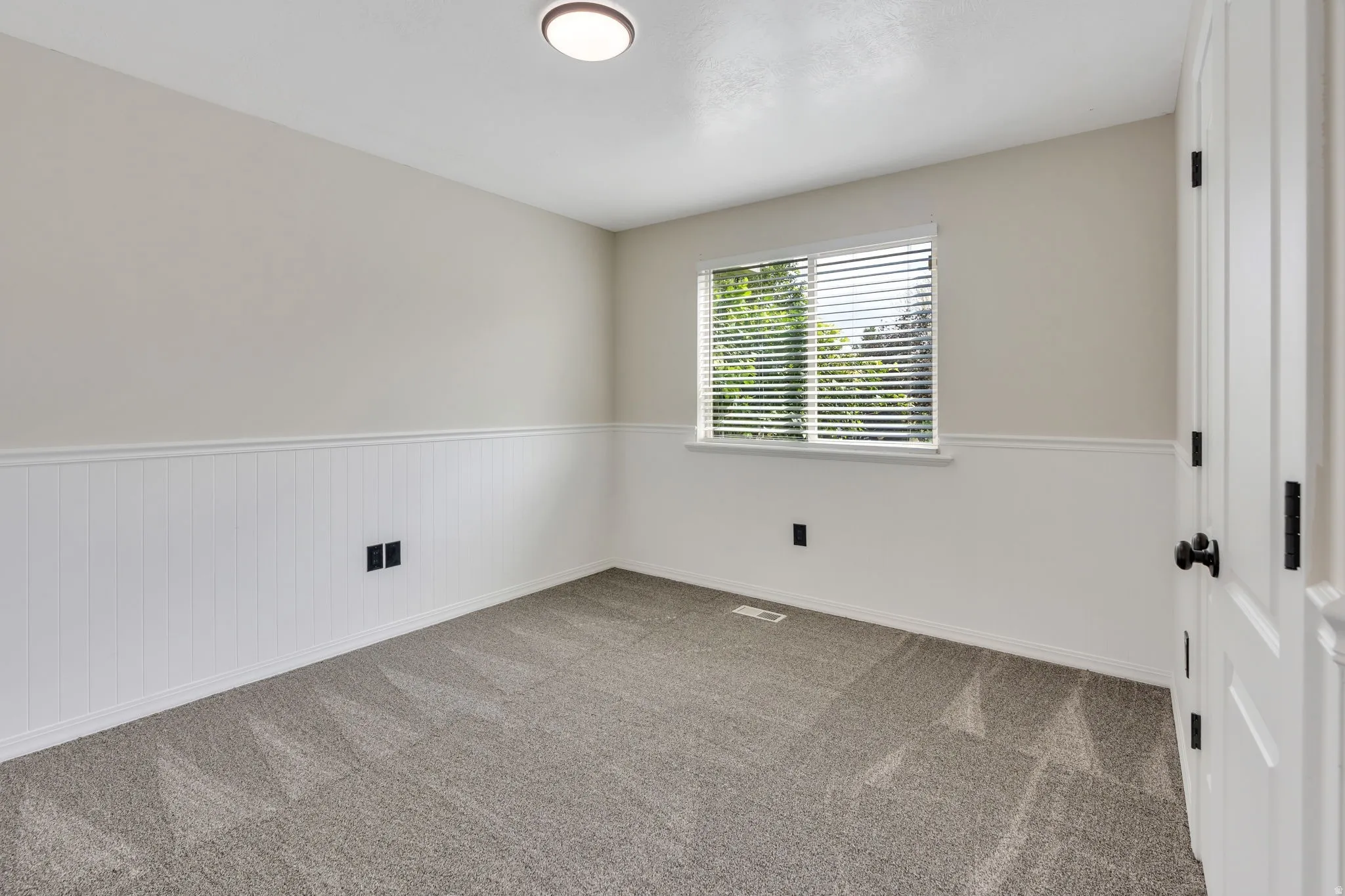 Wall-to-wall carpeting and white wainscoting with a chair rail accent
