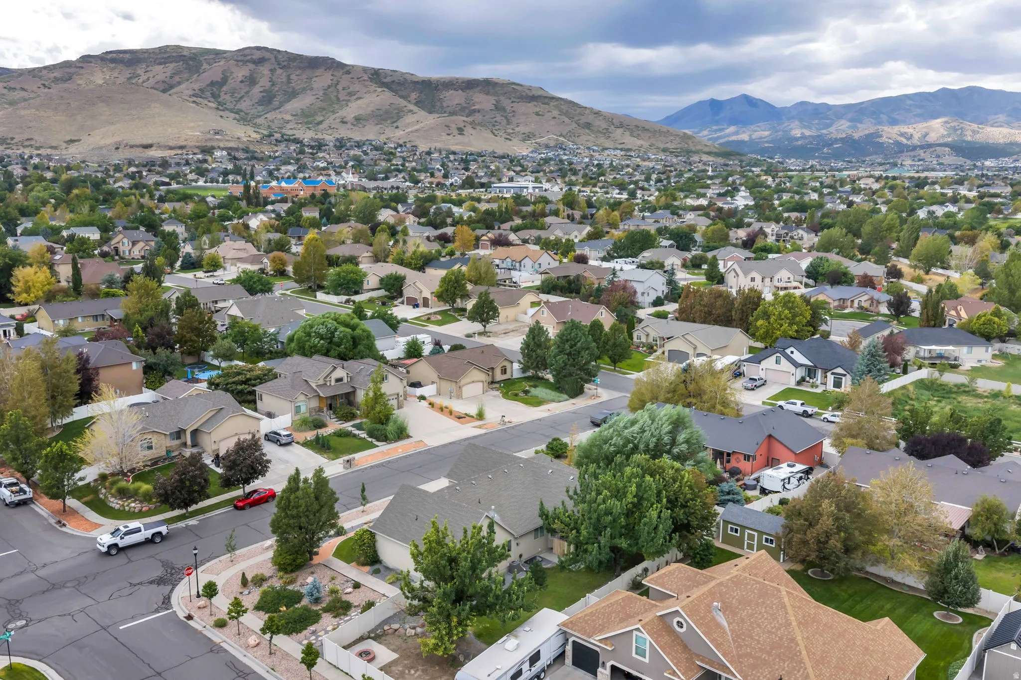 Residential neighborhood with diverse home styles and mature landscaping, framed by distant mountains