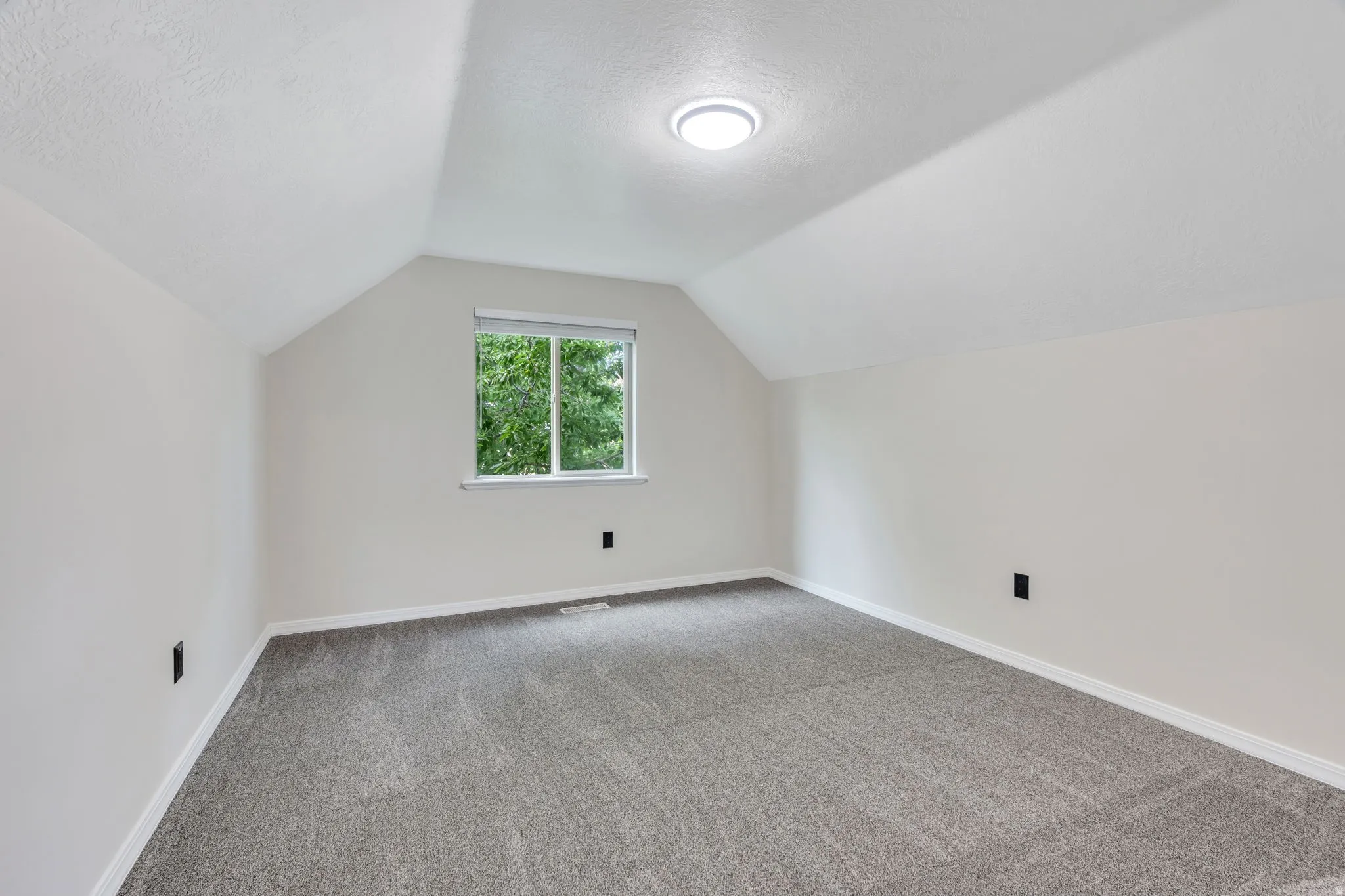 Sloped ceiling room featuring a single window, recessed lighting, and grey carpeting