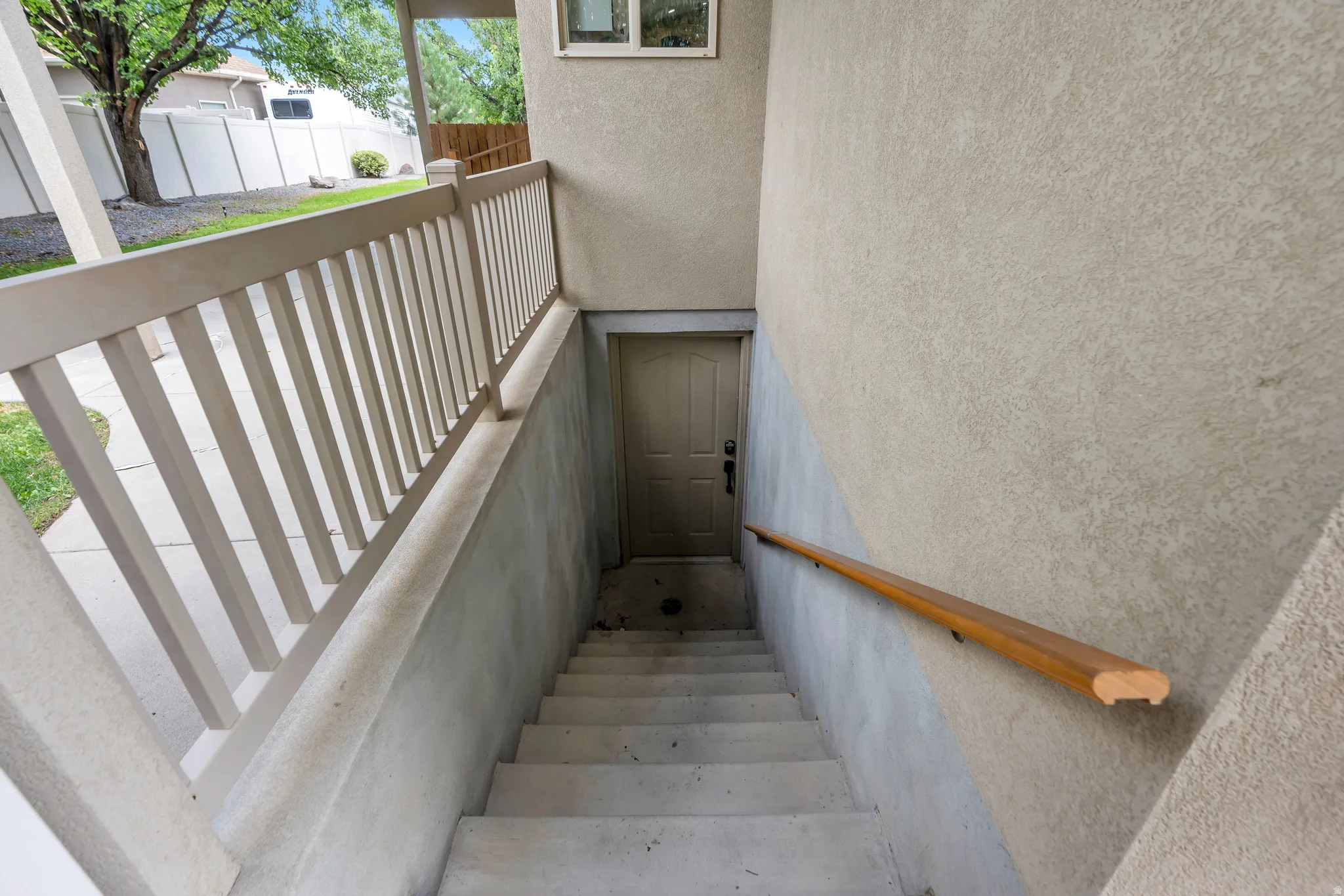 Exterior staircase with a wooden handrail, leading to a solid panel door