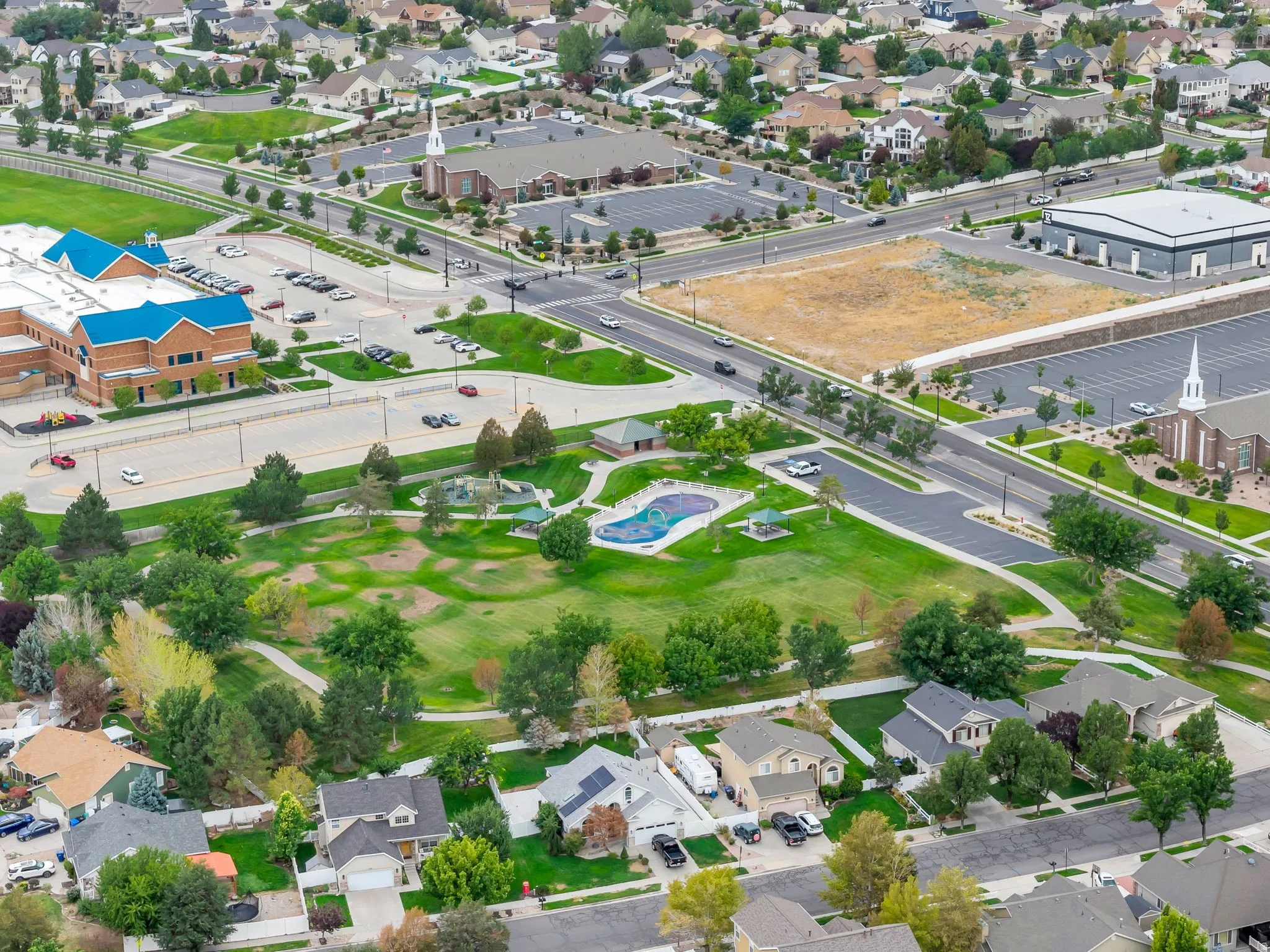 Expansive neighborhood featuring mature trees, residential properties, a large park with green space, and multiple community buildings