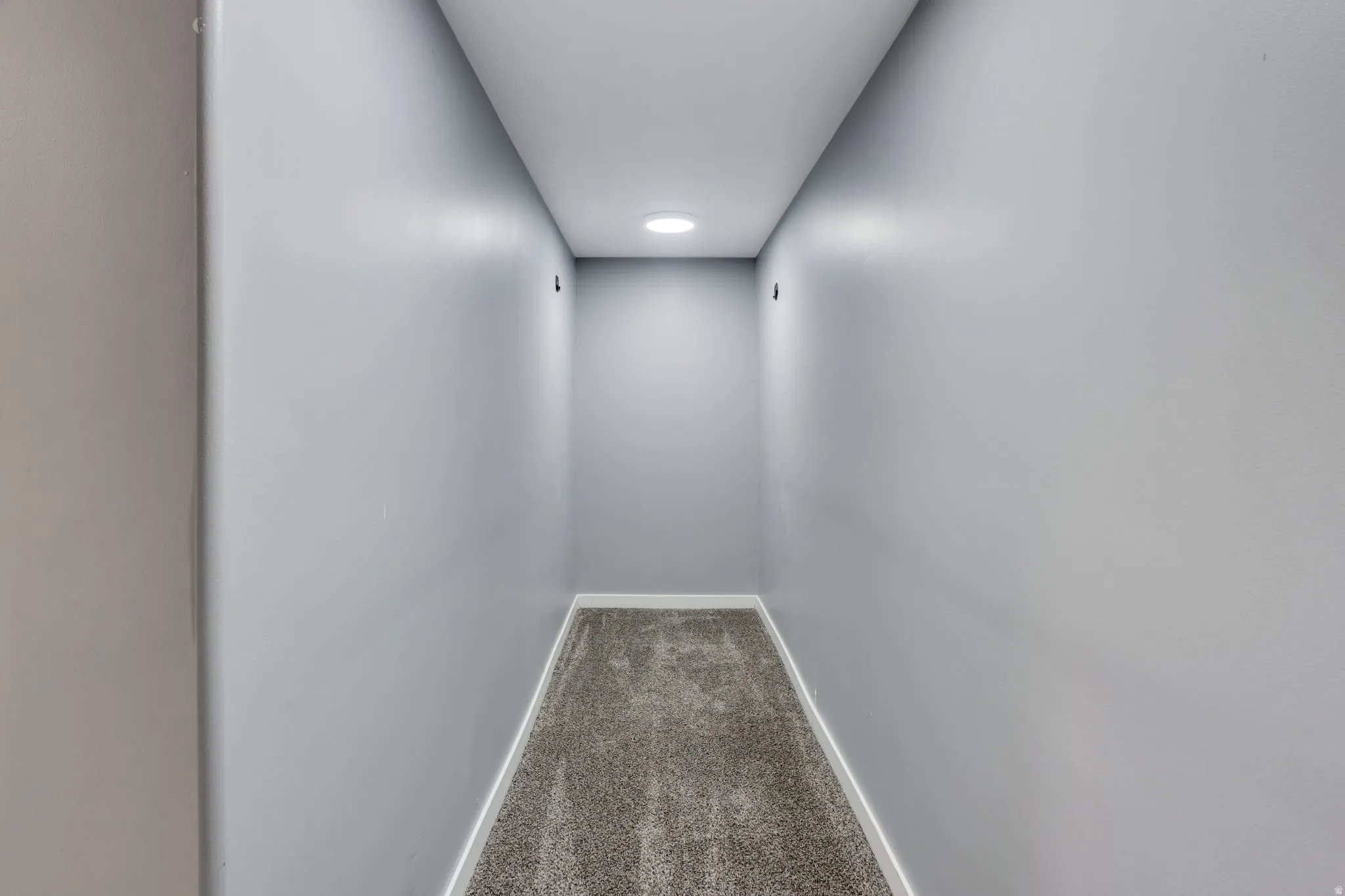 Recessed ceiling lighting illuminating a carpeted hallway with light gray walls