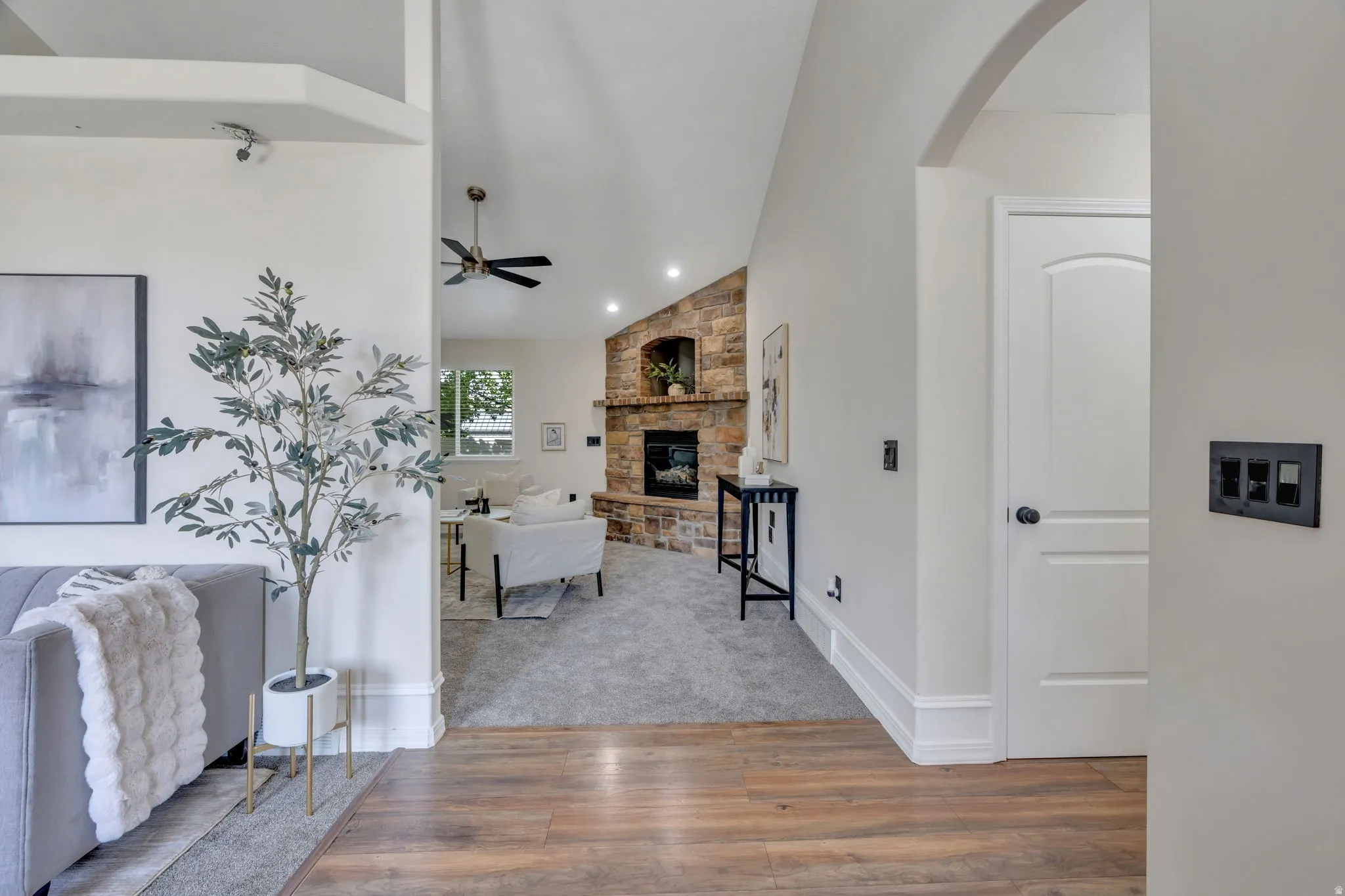 Vaulted ceilings, wood-finish flooring, and a stone fireplace with a hearth
