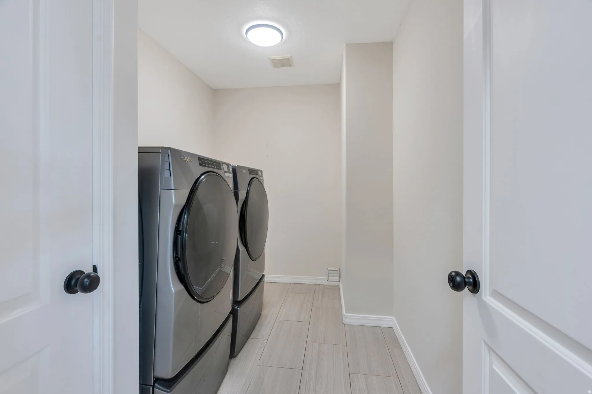 Bright laundry area featuring light-toned walls and tile flooring