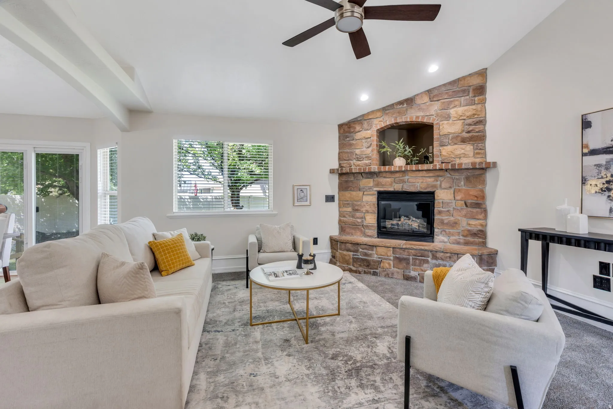 Spacious living area featuring a stone fireplace, wood-finish ceiling fan, recessed lighting, and sliding glass doors
