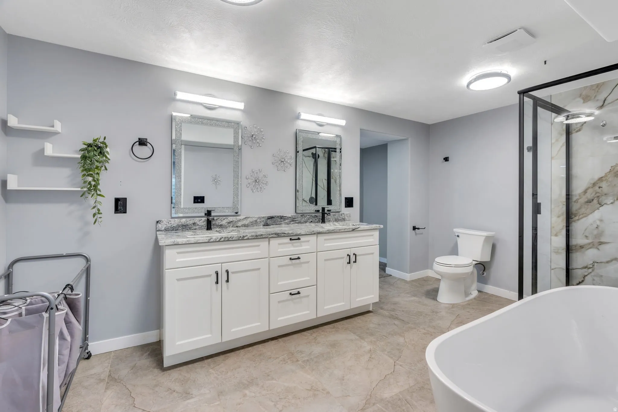 Dual vanity with white cabinetry, stone-finish countertop, and black fixtures