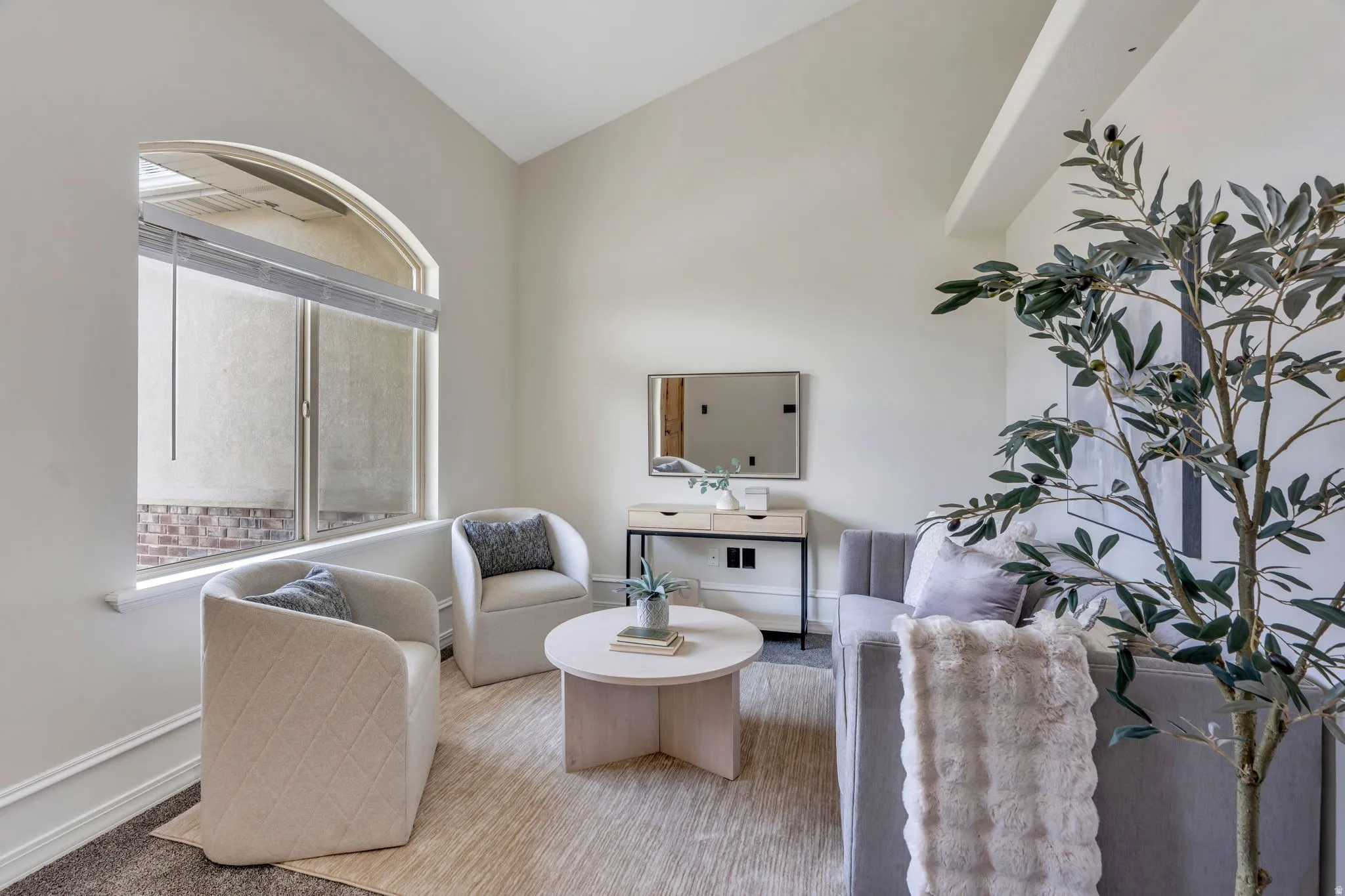 Arched window with roller shades, vaulted ceiling, and crown molding