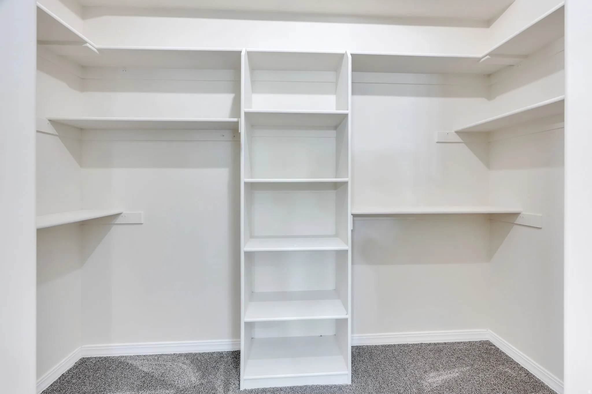 Built-in shelving with multiple shelves and white finishes, complemented by gray carpeting