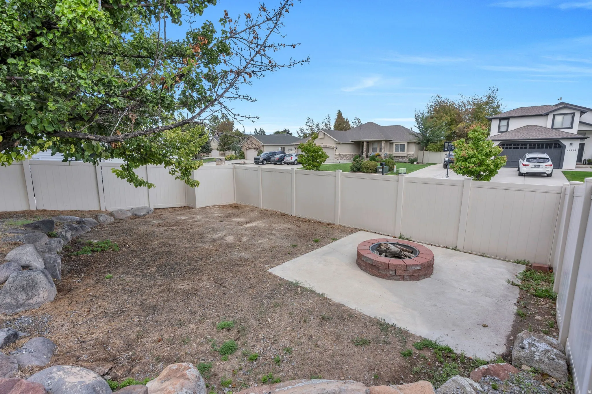 Enclosed backyard featuring a fire pit on a concrete pad, a rock border, and a privacy fence