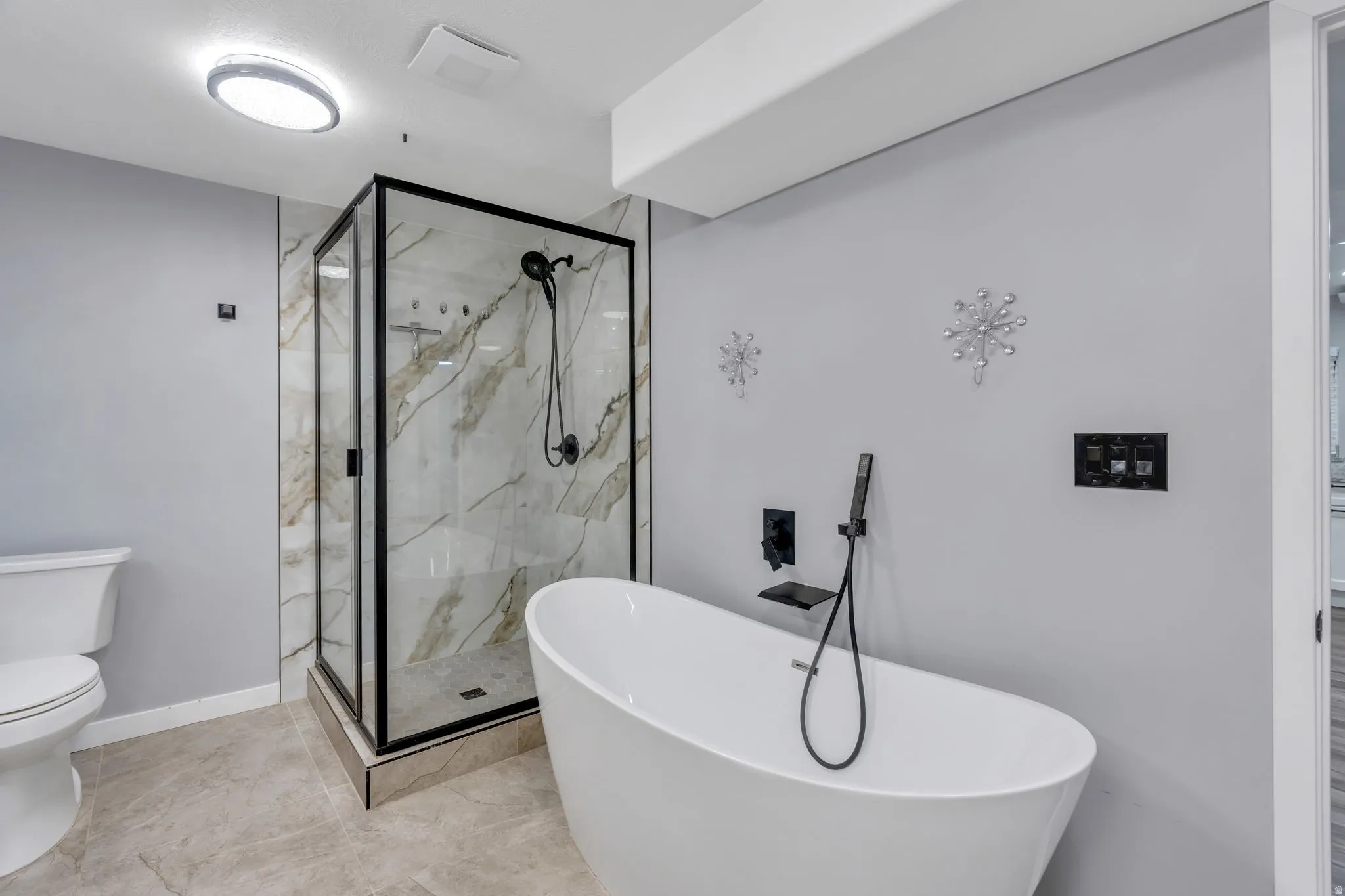 Contemporary bathroom featuring a freestanding soaking tub, glass-enclosed shower with tiled walls, and stone-look floor tiles