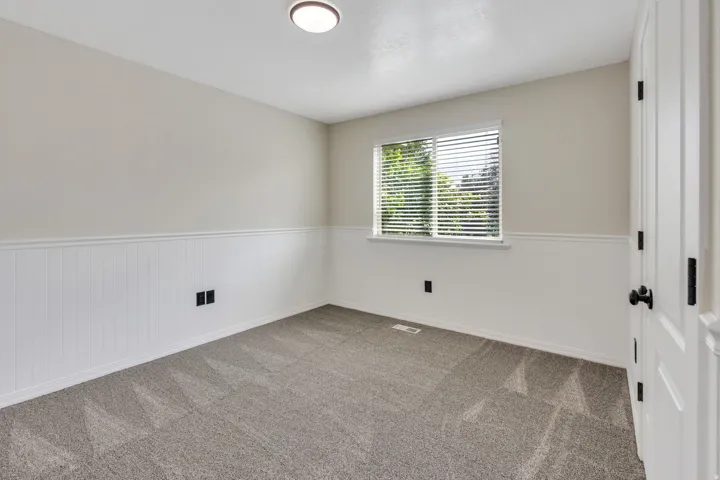 Wall-to-wall carpeting and white wainscoting with a chair rail accent