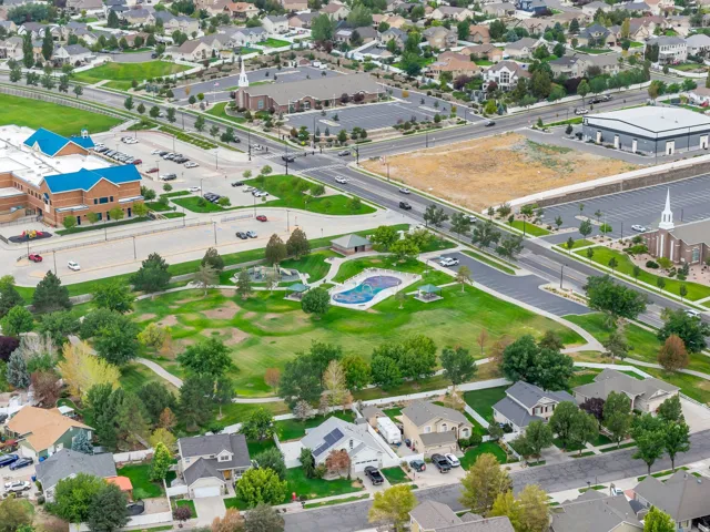 Expansive neighborhood featuring mature trees, residential properties, a large park with green space, and multiple community buildings