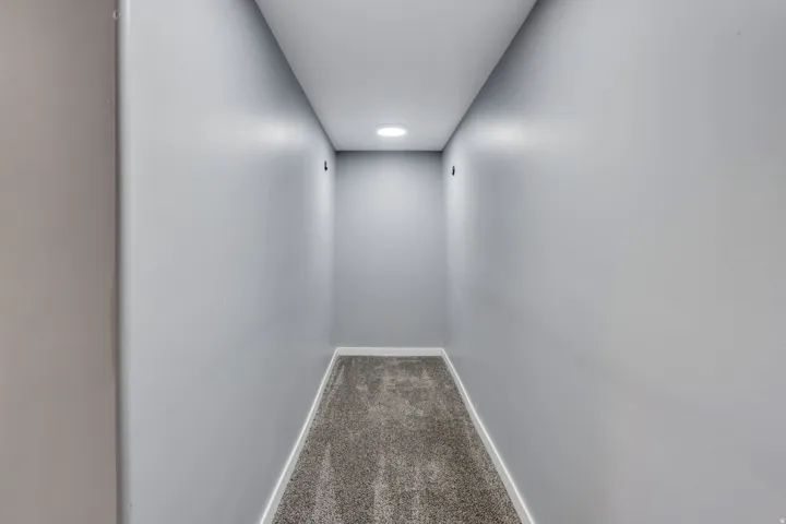 Recessed ceiling lighting illuminating a carpeted hallway with light gray walls