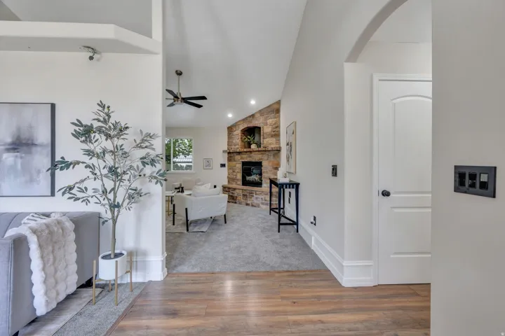 Vaulted ceilings, wood-finish flooring, and a stone fireplace with a hearth