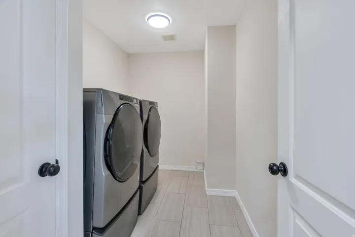 Bright laundry area featuring light-toned walls and tile flooring