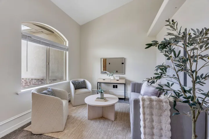 Arched window with roller shades, vaulted ceiling, and crown molding