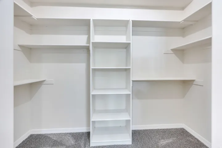 Built-in shelving with multiple shelves and white finishes, complemented by gray carpeting