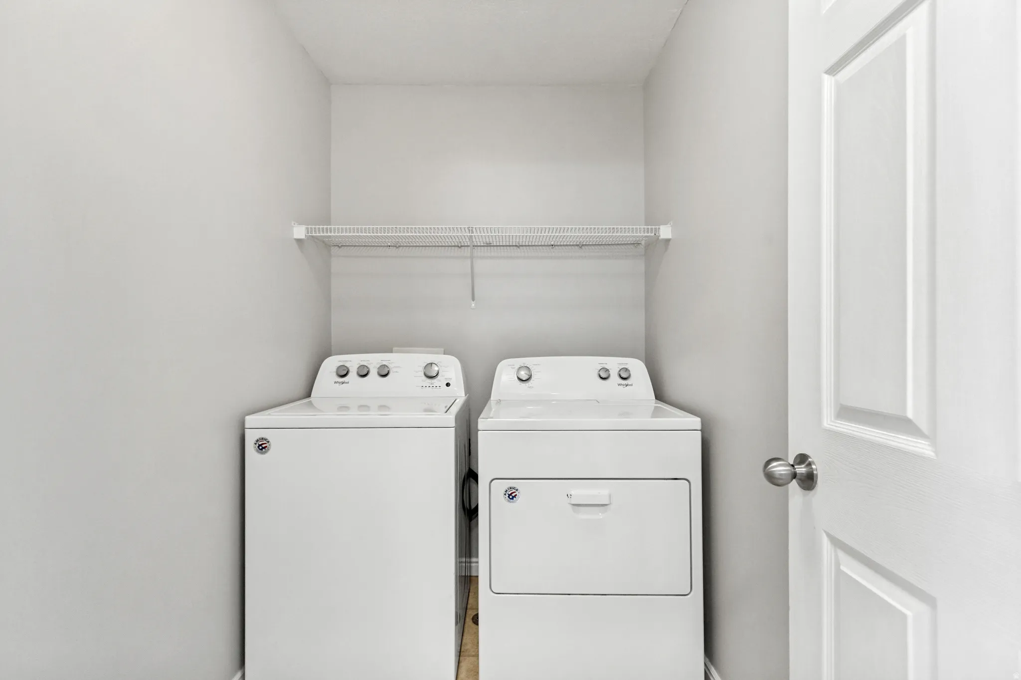 Laundry area featuring white walls, a white wire shelf, and a white paneled door
