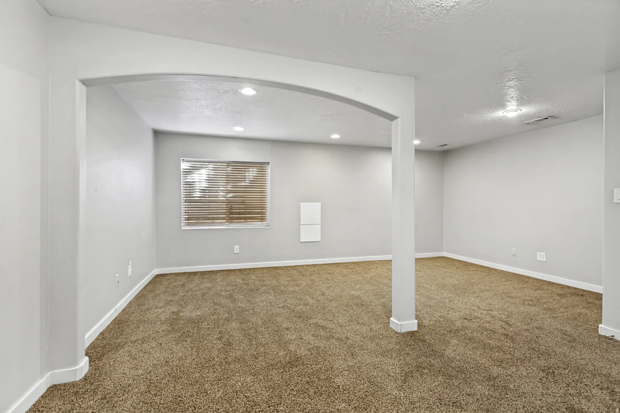 Carpeted room with recessed lighting and a window featuring horizontal blinds