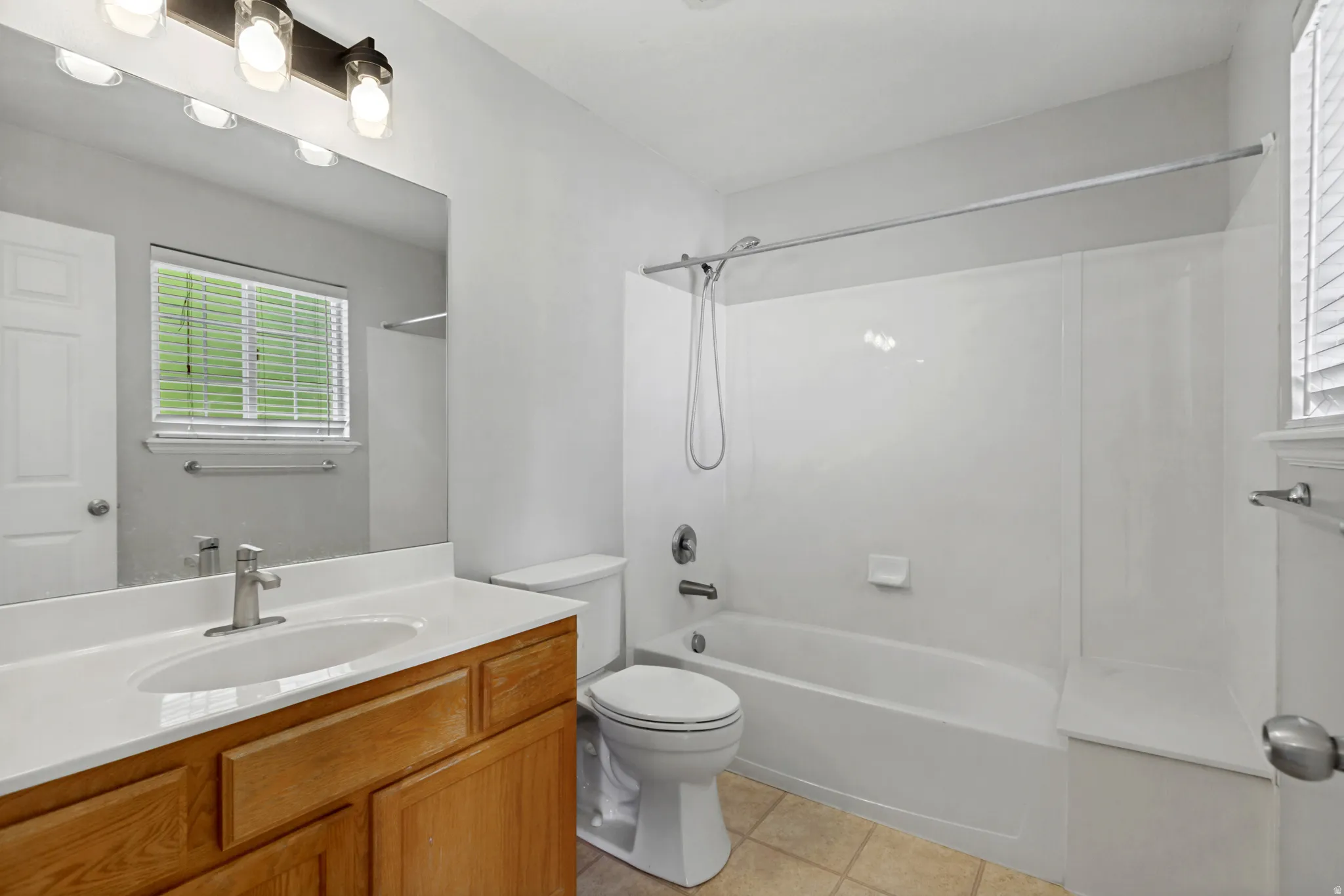 Bathroom featuring a wood-finish vanity with an integrated sink, a full-width mirror, and an overhead vanity light fixture