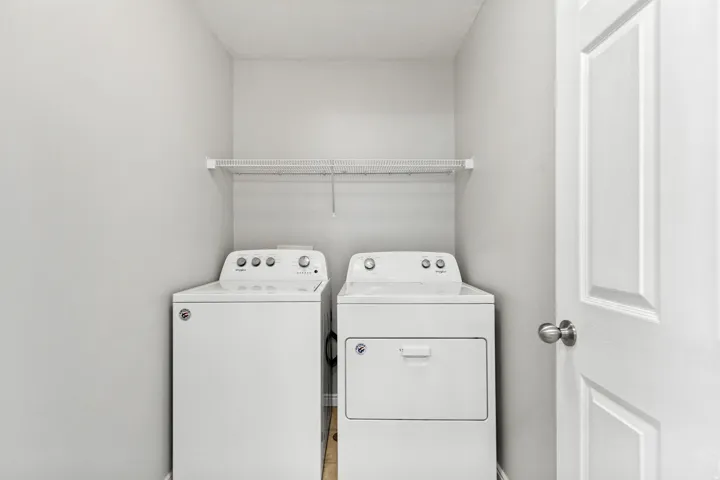 Laundry area featuring white walls, a white wire shelf, and a white paneled door