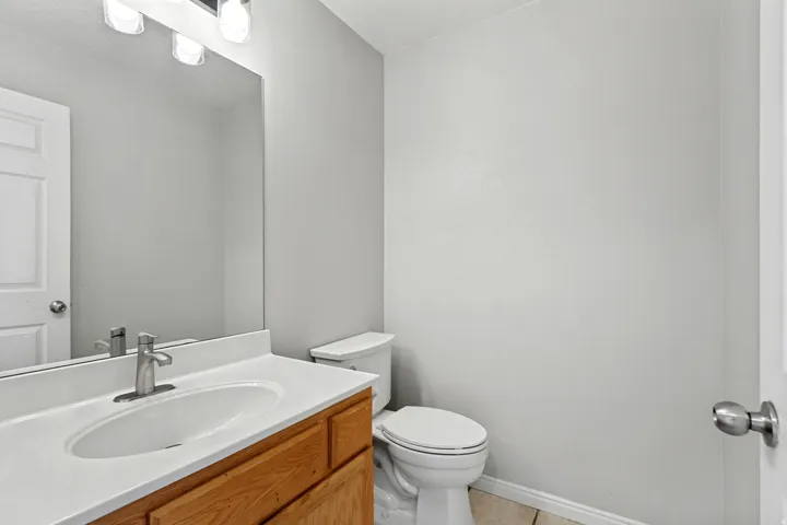 Powder room featuring a single vanity with wood-finish cabinetry, white countertop, and an undermount sink with a brushed nickel faucet