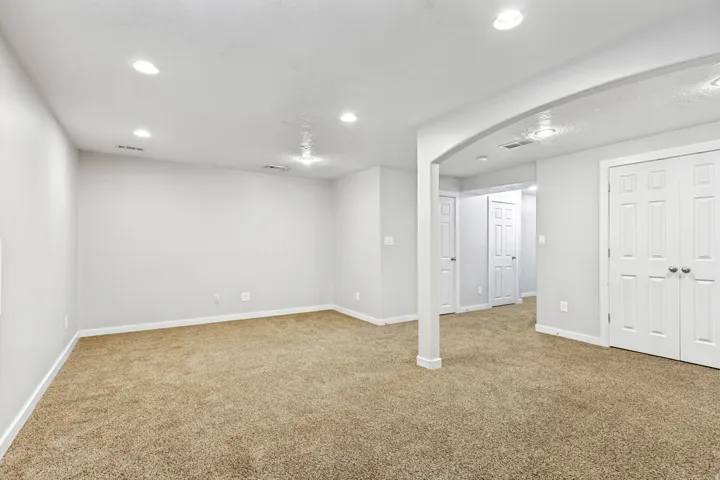 Recessed lighting, light-toned carpeting, white interior doors, and a column detail