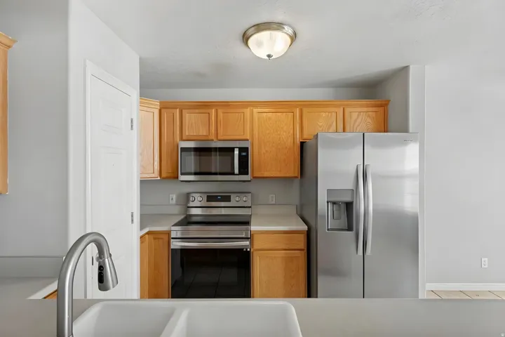 Kitchen featuring light wood cabinetry, stainless steel appliances, and white countertops
