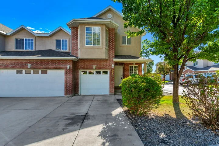 Brick facade with tan stucco accents, an attached two-car garage, and a single-car garage