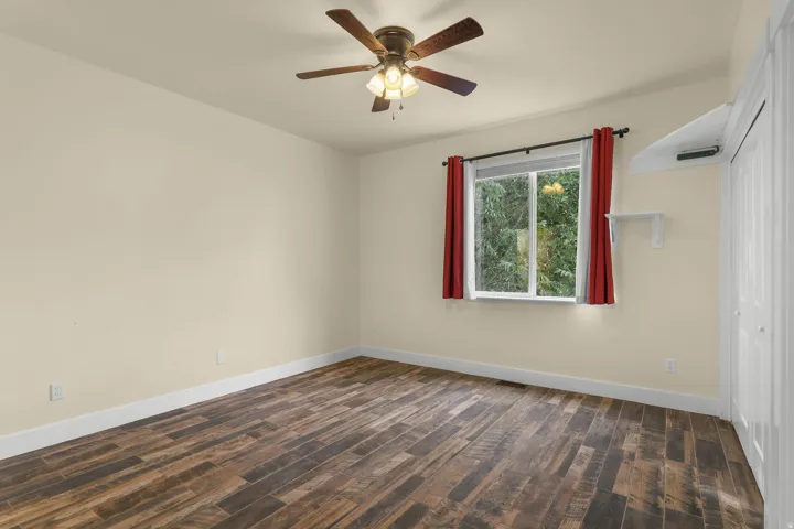 Wood-finish flooring, ceiling fan with integrated lighting, double-pane window, built-in shelving, and closet with bi-fold doors