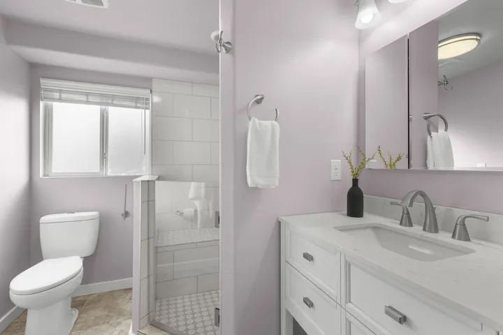 White vanity with integrated sink, brushed nickel fixtures, and a framed mirror